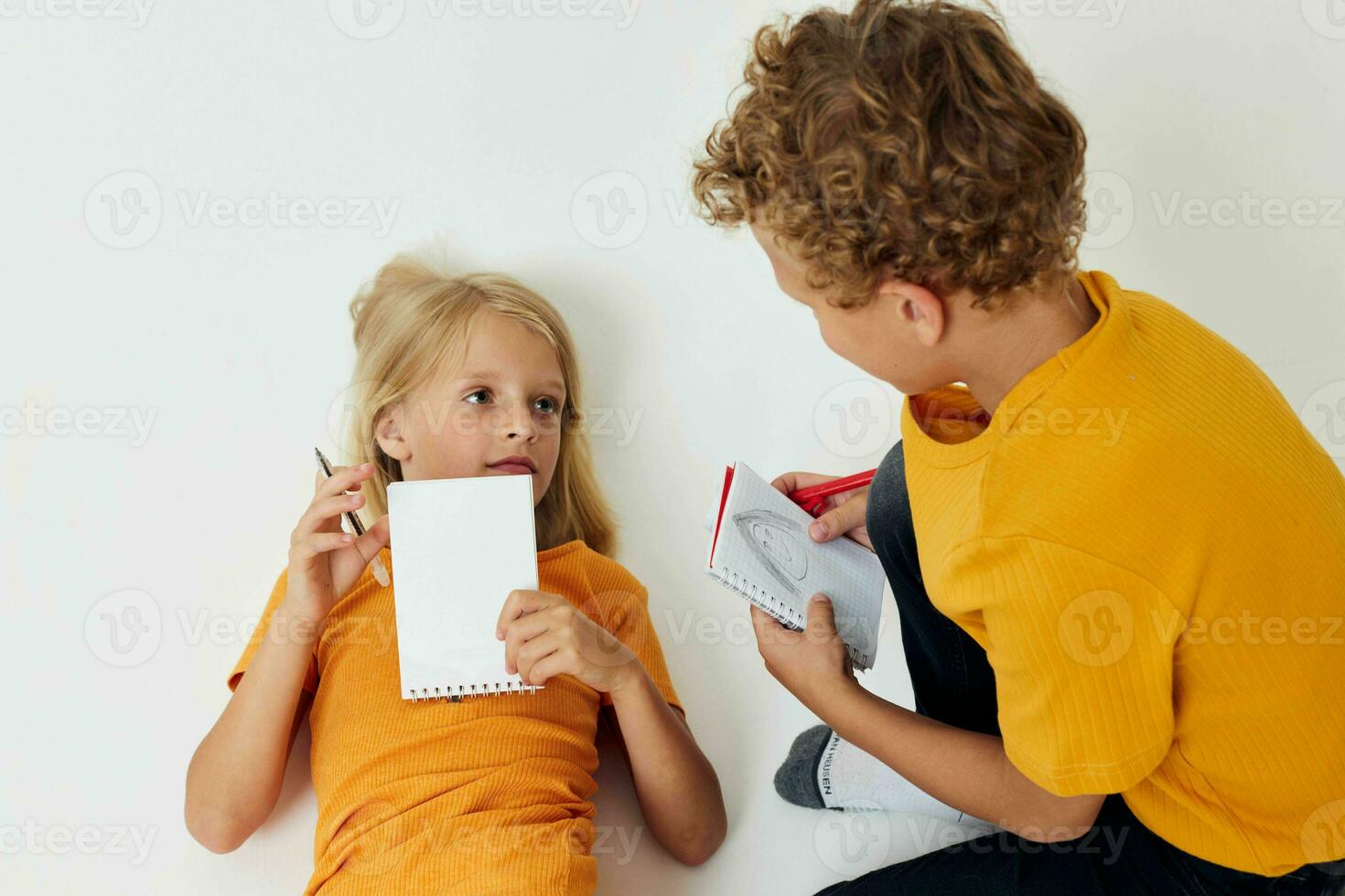 picture of positive boy and girl drawing in notebooks lying on the floor light background unaltered photo