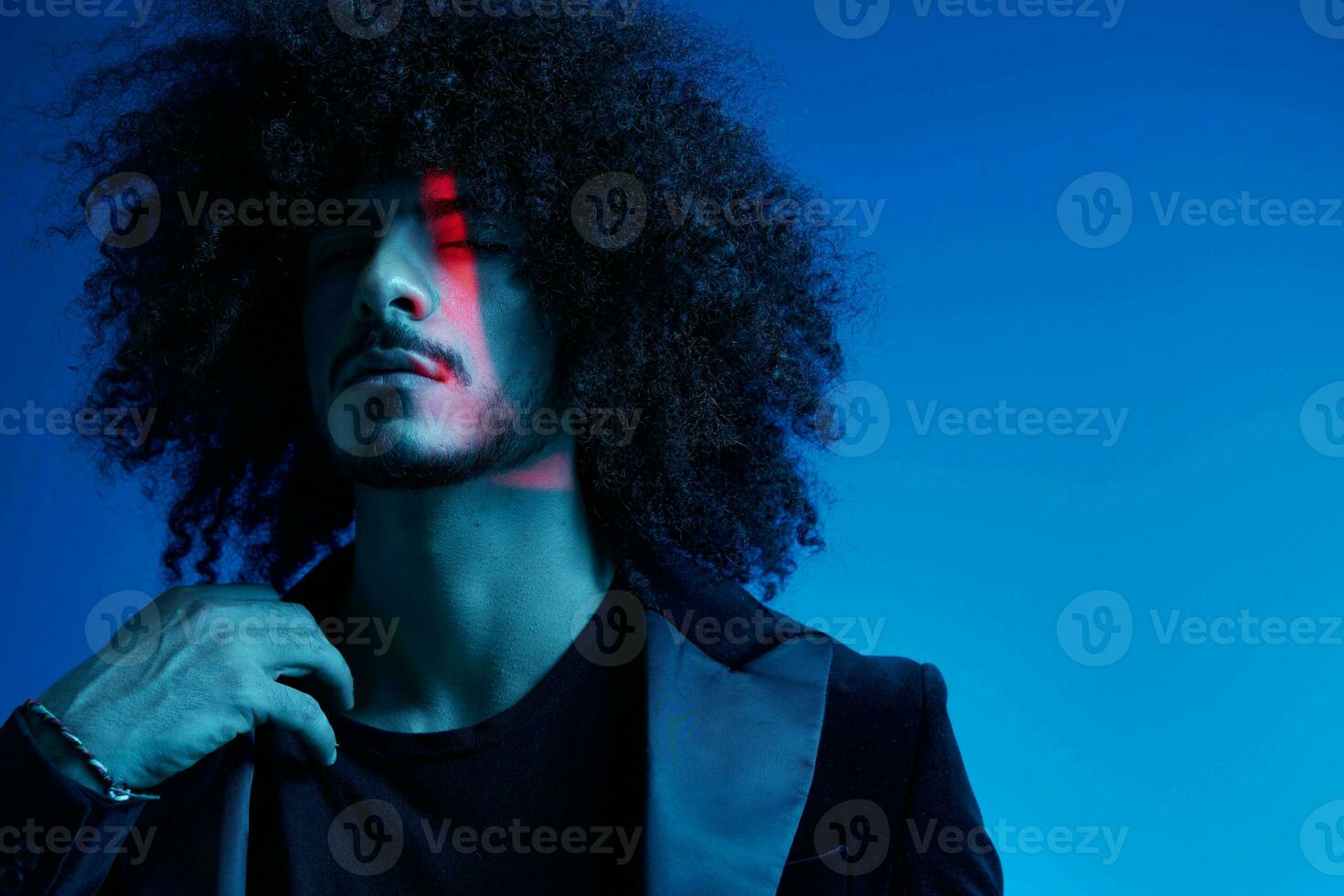 Fashion portrait of a man with curly hair on a blue background, multinational, colored light, trendy, modern concept. photo
