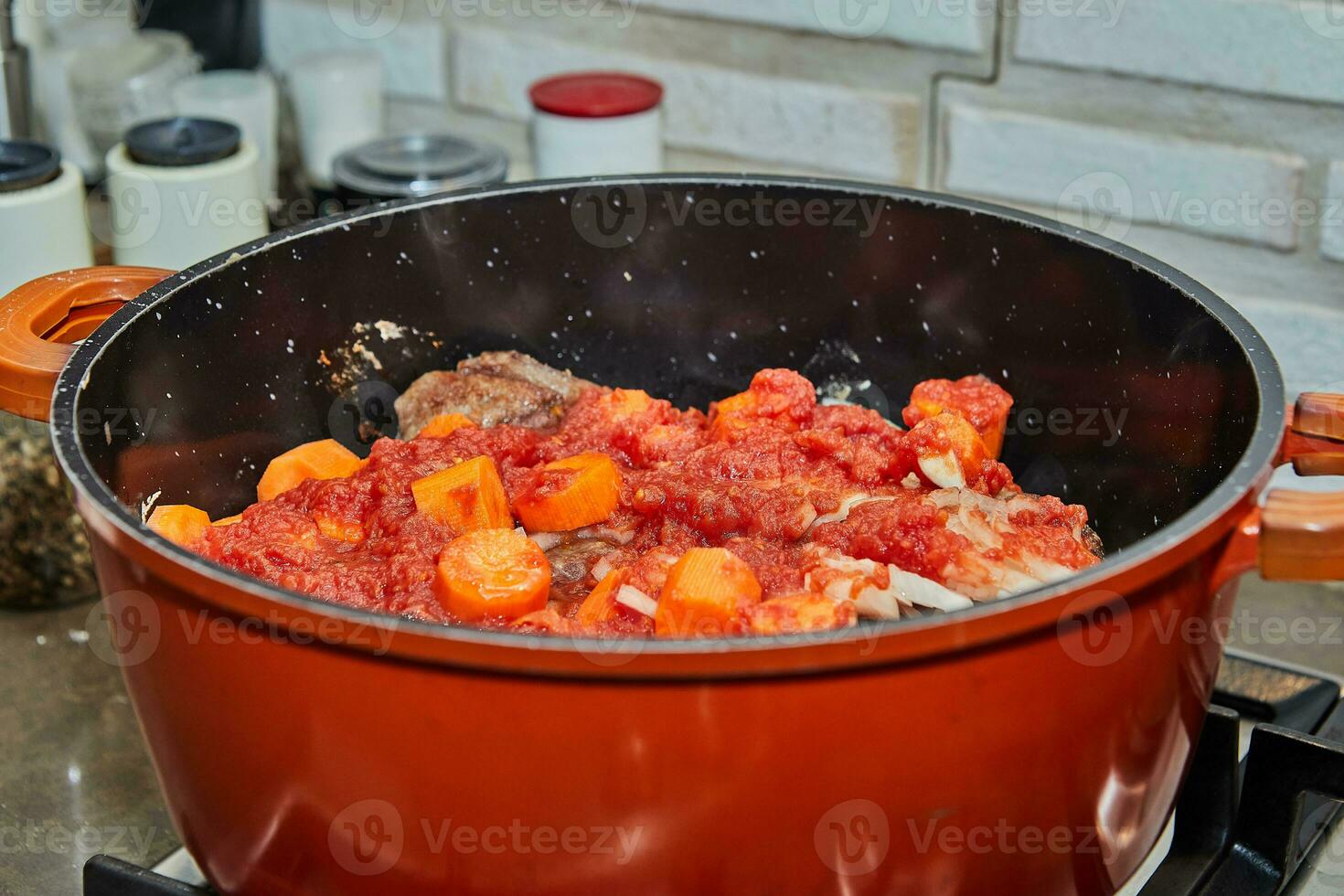 Ossobuco simmers in saucepan with carrots and sauce over low heat photo