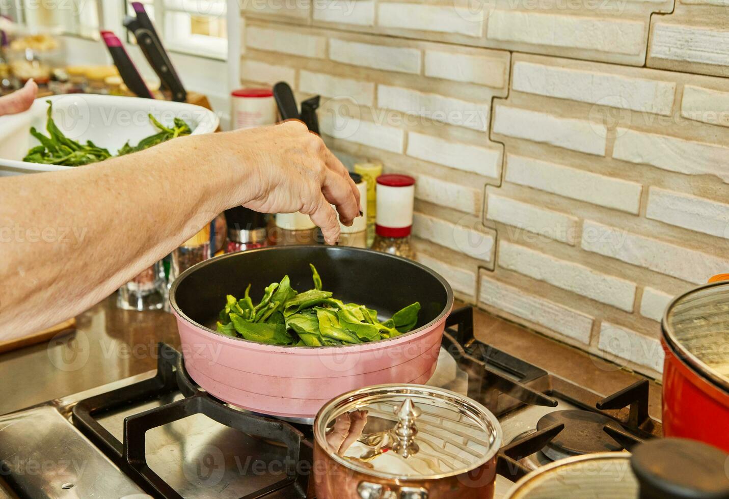 Chef is frying sorrel in frying pan in oil on gas stove photo