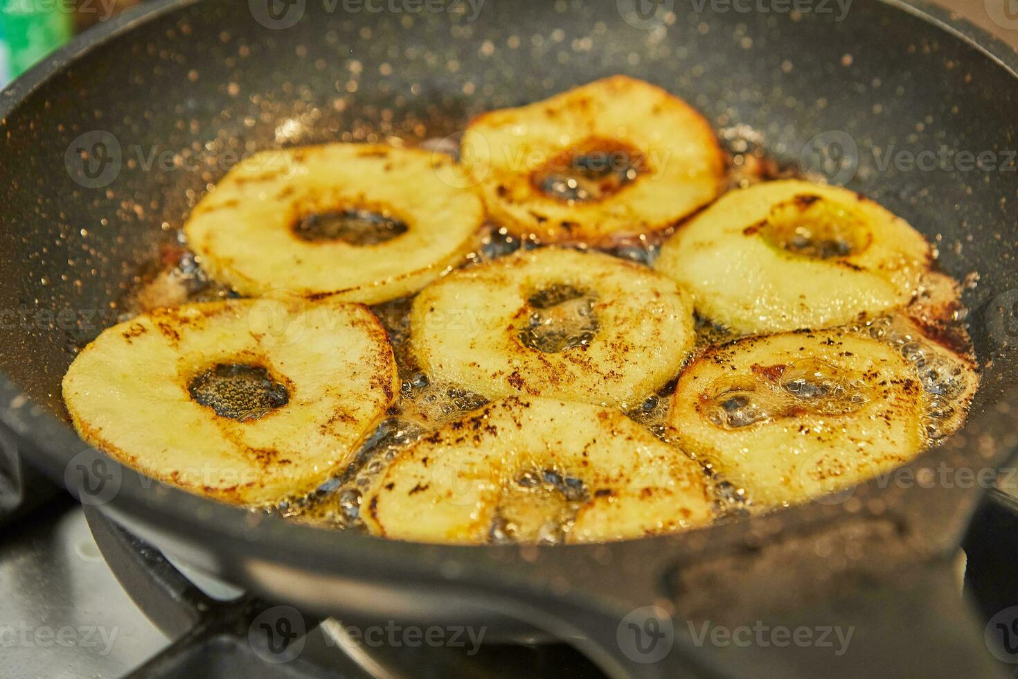 Sliced apples are fried in pan on gas stove photo