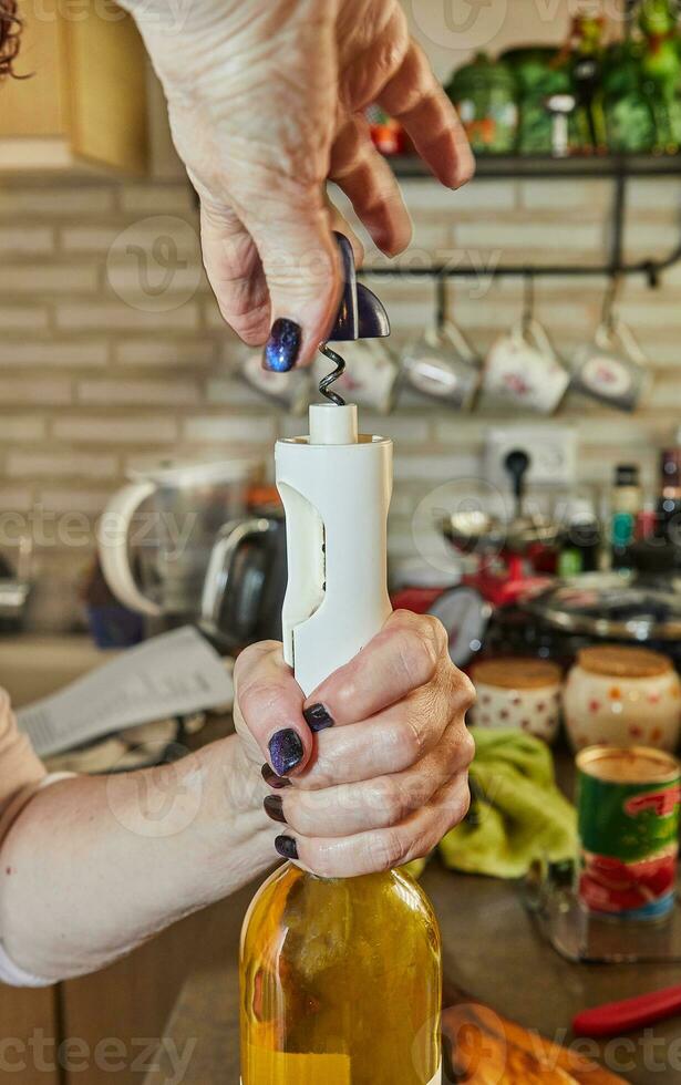 mujer abre botella de blanco vino con especial sacacorchos foto