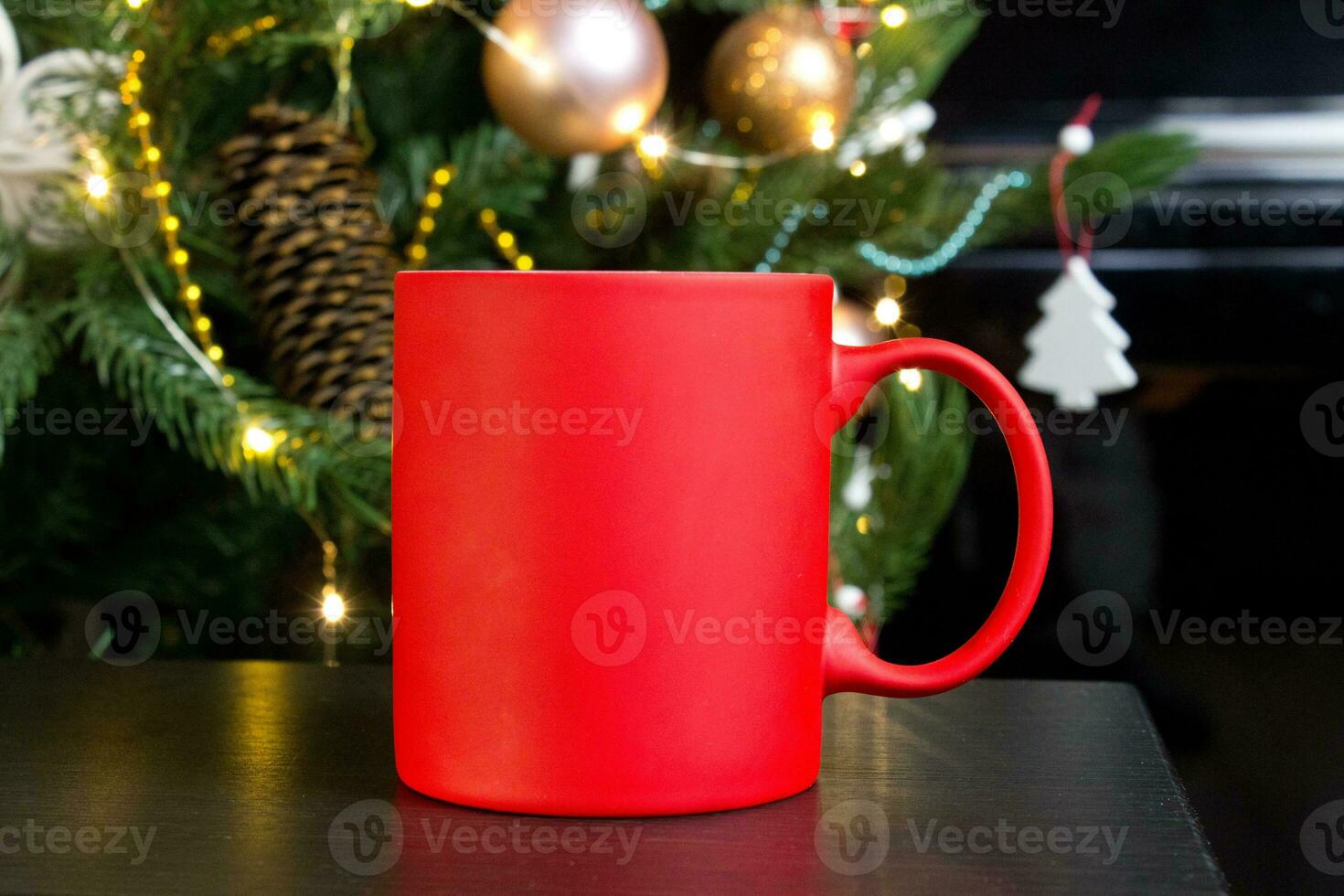 Blank red mug with christmas tree on background,mat tea or coffee cup with christmas and new year decoration,vertical mock up with ceramic mug for hot drinks,empty gift print template photo