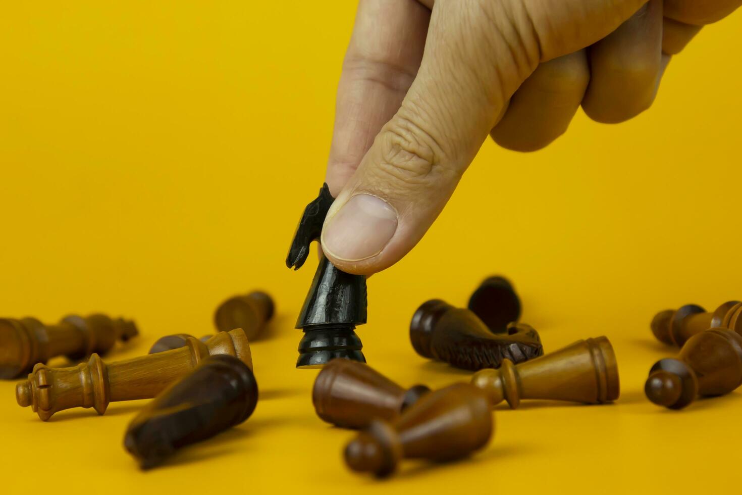 A hand placing the Realistic horse on bright yellow background with copy space. Chess piece. Minimal creative battle concept photo
