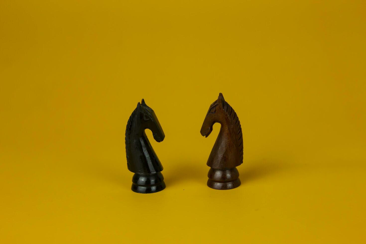 Two horses facing each other for fighting and Chess horse piece  isolated yellow background, used for success and stategy concept photo