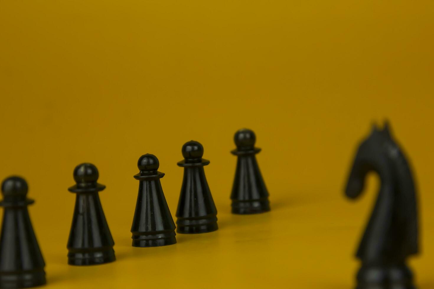 A black horse Chess standing for facing to the team and fighting the problem on business on  isolated yellow background, used for success and stategy concept photo