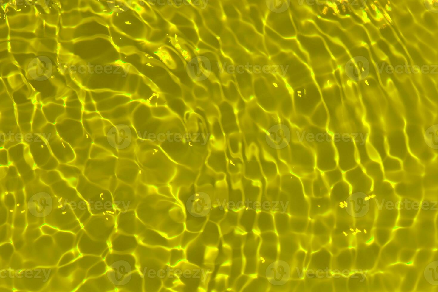 Yellow water with ripples on the surface. Defocus blurred transparent gold colored clear calm water surface texture with splashes and bubbles. Water waves with shining pattern texture background. photo