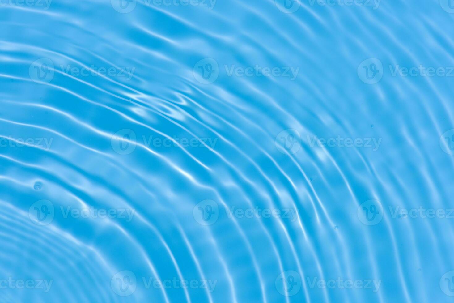 Blue water with ripples on the surface. Defocus blurred transparent blue colored clear calm water surface texture with splashes and bubbles. Water waves with shining pattern texture background. photo