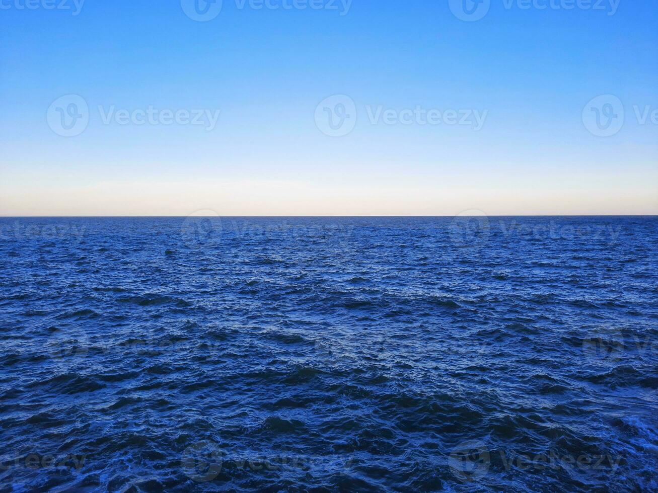 Blue sky and ocean with ripples on the surface. Defocus blurred transparent blue sea surface texture with splashes and bubbles. Water waves with shining pattern texture background. photo