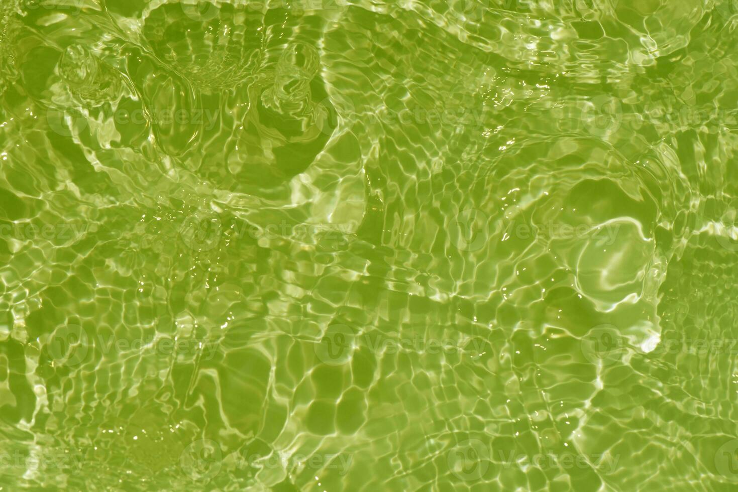 Light green water with ripples on the surface. Defocus blurred transparent colored clear calm water surface texture with splashes and bubbles. Water waves with shining pattern texture background. photo