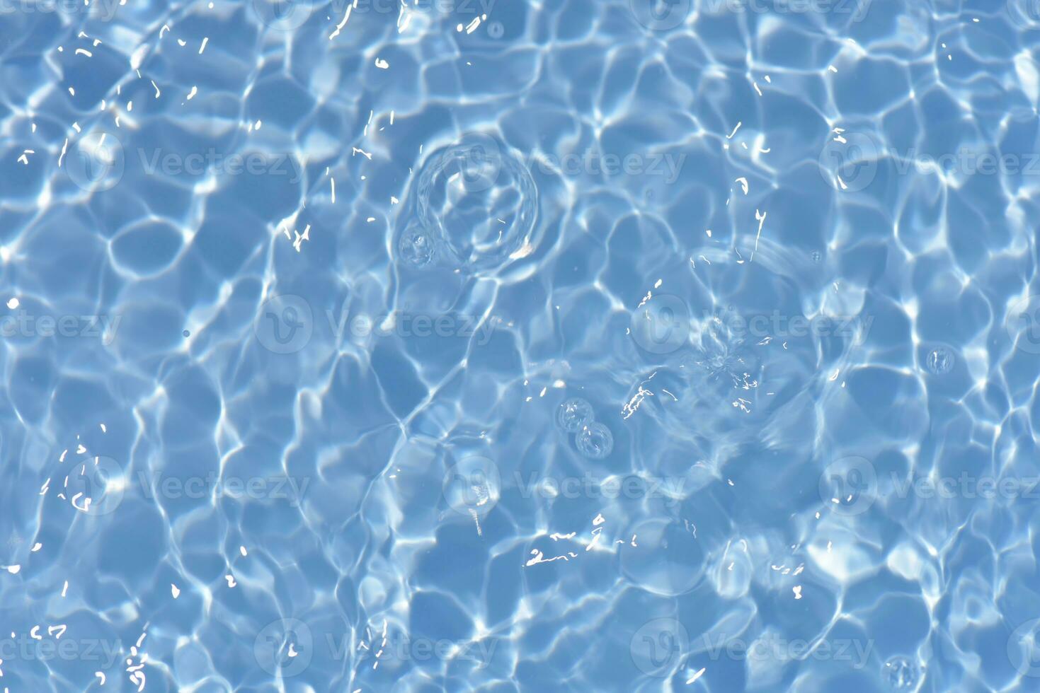 Blue water with ripples on the surface. Defocus blurred transparent blue colored clear calm water surface texture with splashes and bubbles. Water waves with shining pattern texture background. photo