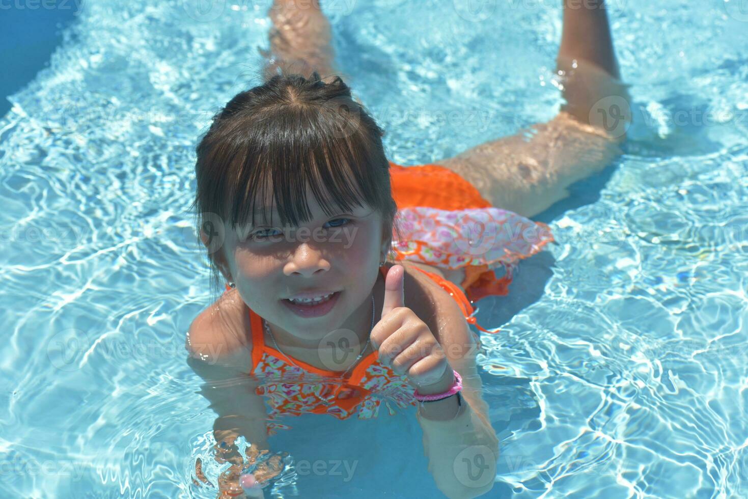 Happy little girl swimming pool on a hot summer day. Kids learn to swim. Child water toys. Children play in tropical resorts. Family beach vacation. photo