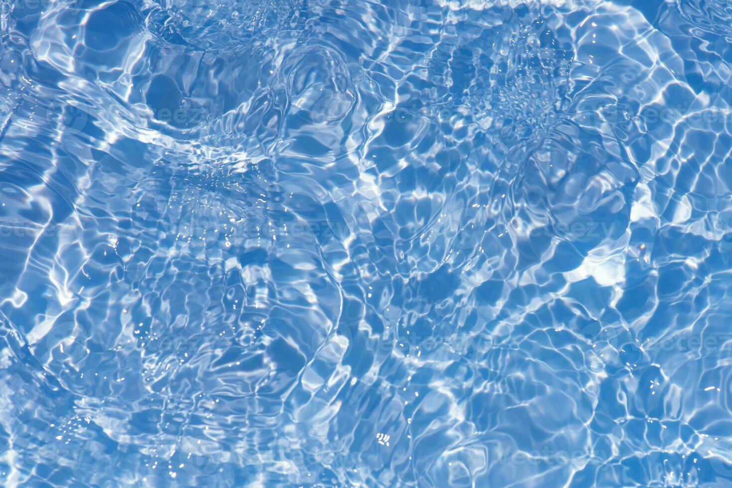 Blue water with ripples on the surface. Defocus blurred transparent blue colored clear calm water surface texture with splashes and bubbles. Water waves with shining pattern texture background. photo