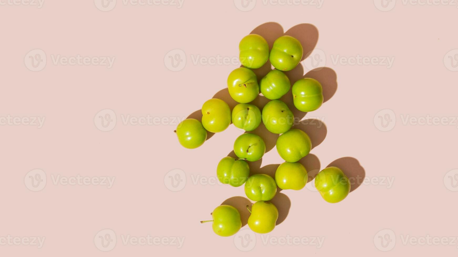 Green fresh raw plums on pink background, copy space, mockup, isolated photo