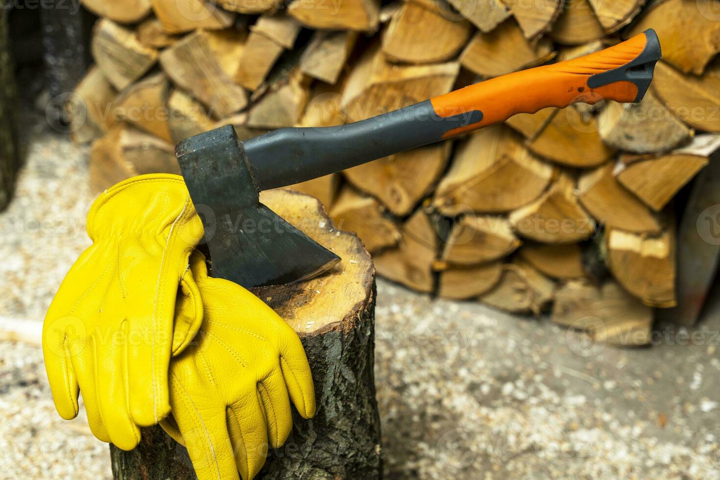 axe stuck in a wooden deck and protective yellow leather gloves photo
