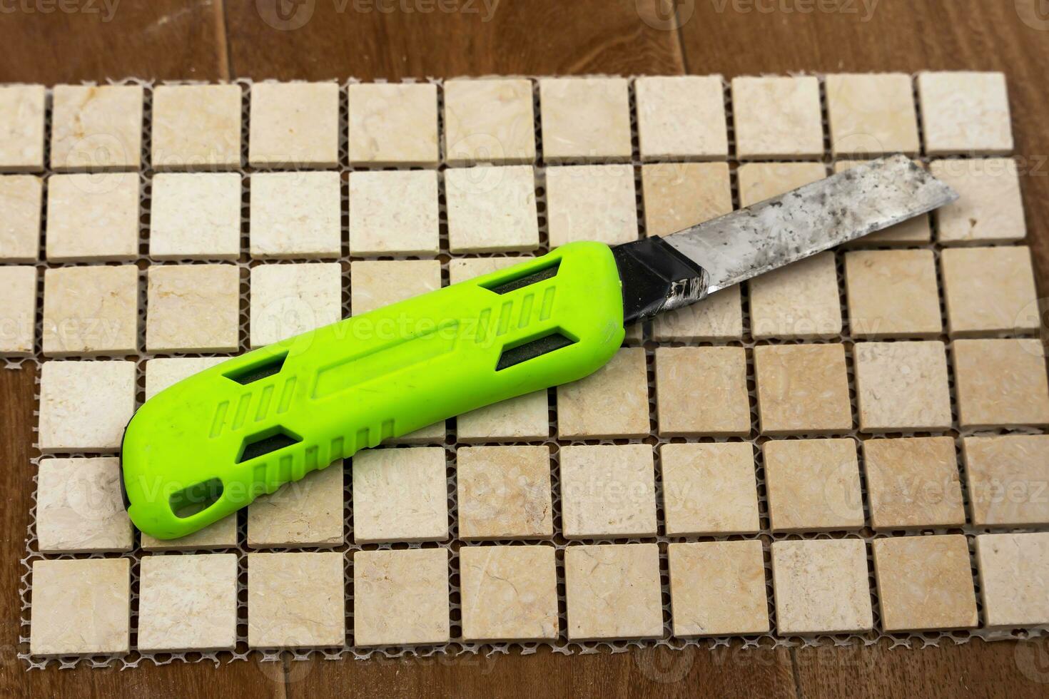 construction knife with replaceable blades lying on a ceramic tile photo