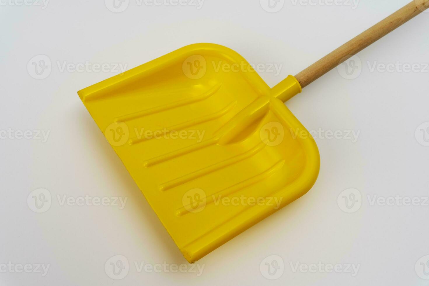 bright yellow plastic children's snow shovel with wooden handle photo