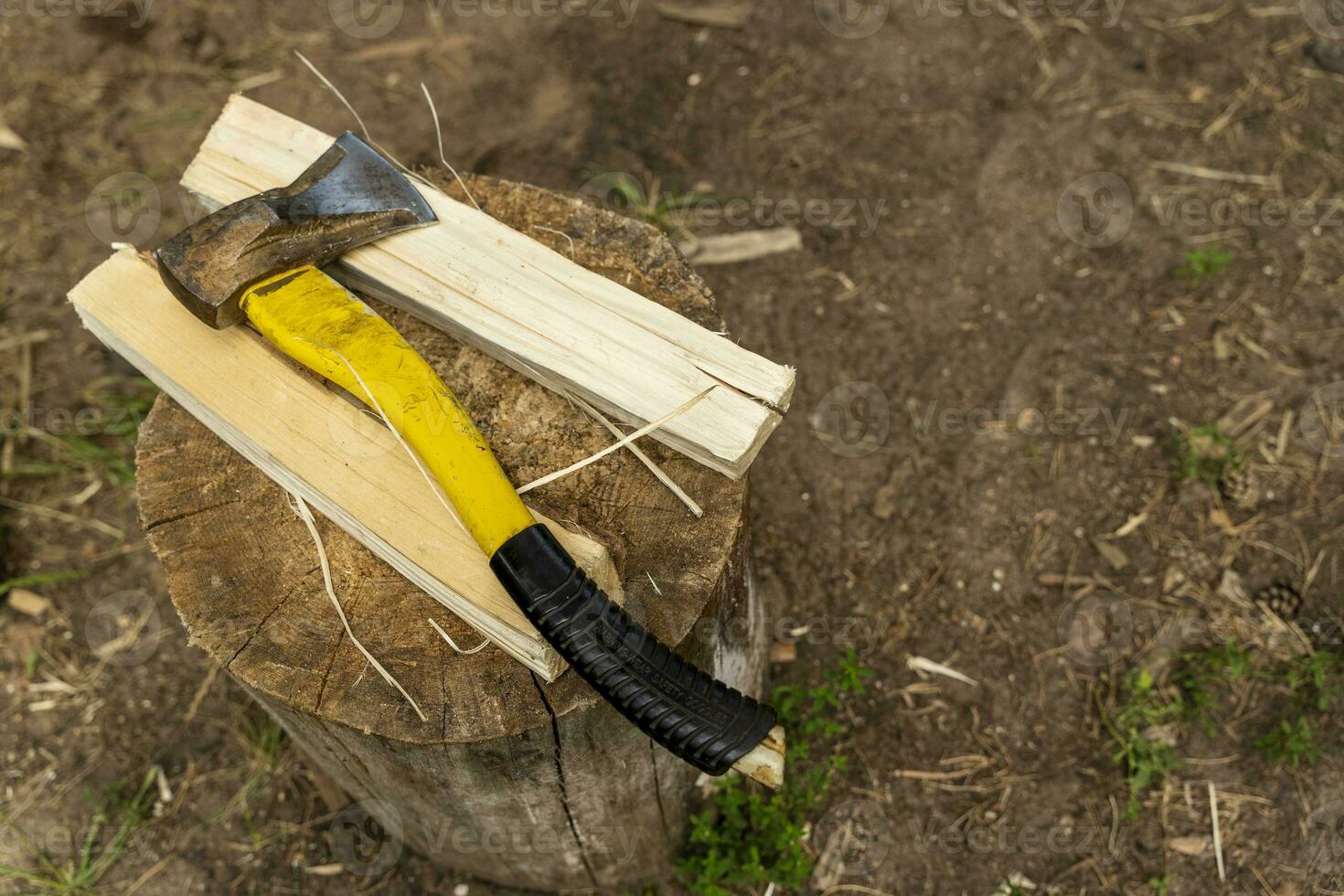 an axe with a plastic handle and a split wooden log on a stump photo