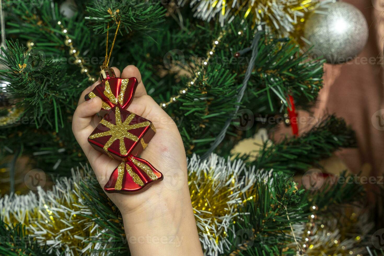 A child dresses up a Christmas tree with toys photo