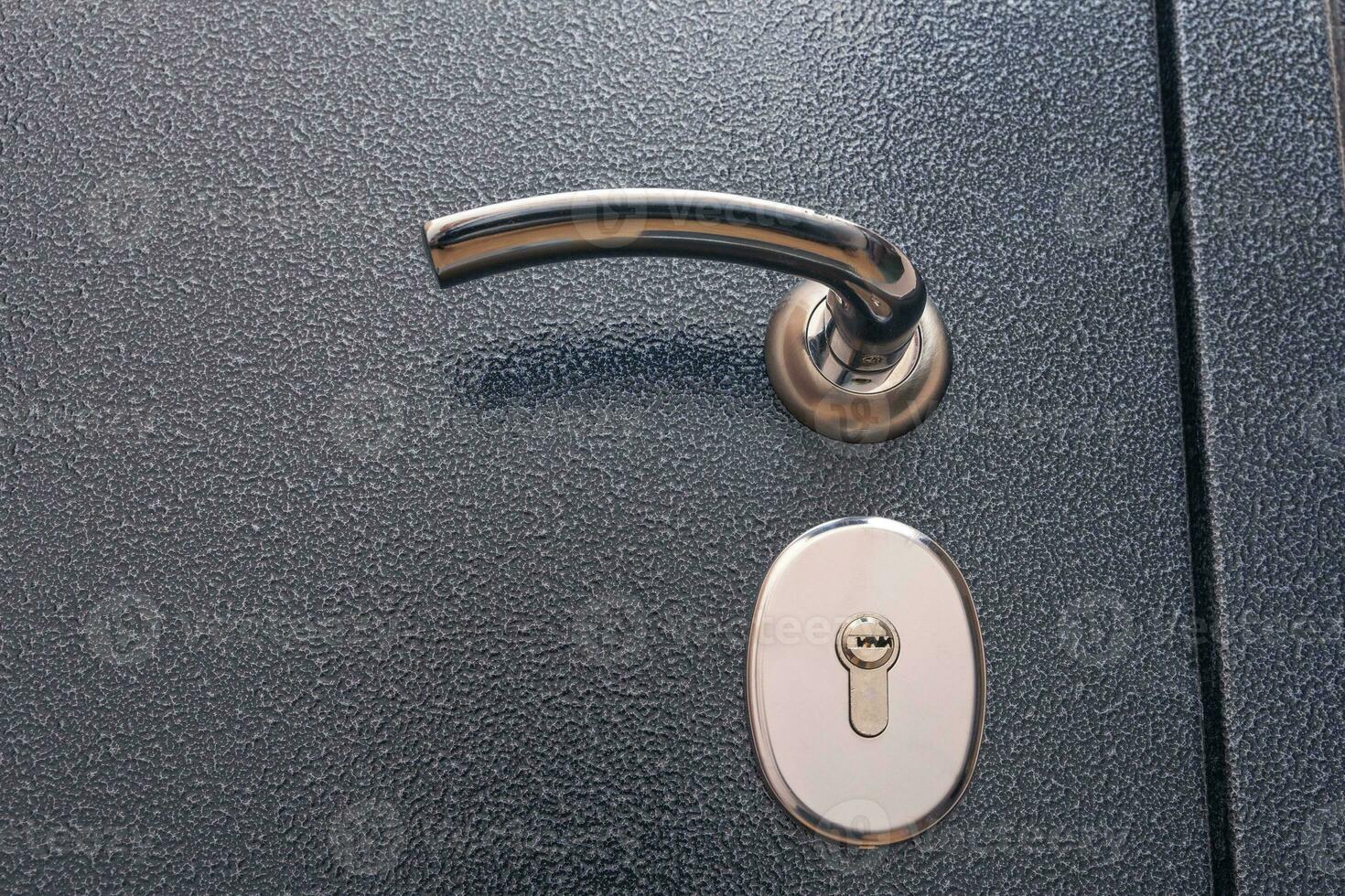 modern reliable metal entrance door. shiny handle, lock. close-up photo