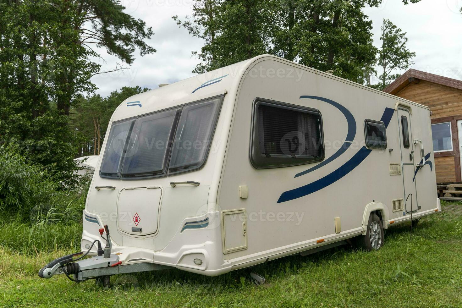 Camper trailer for traveling standing on shore of the lake in summer photo