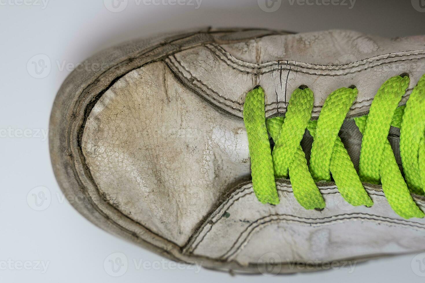 worn old torn white sneakers with colored laces on a white background photo