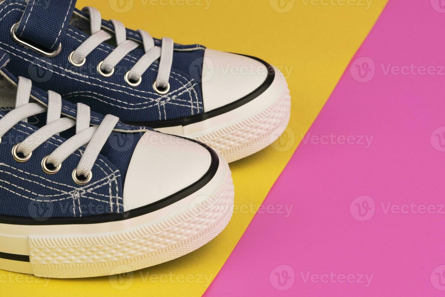 a pair of blue sneakers on a yellow-pink background photo