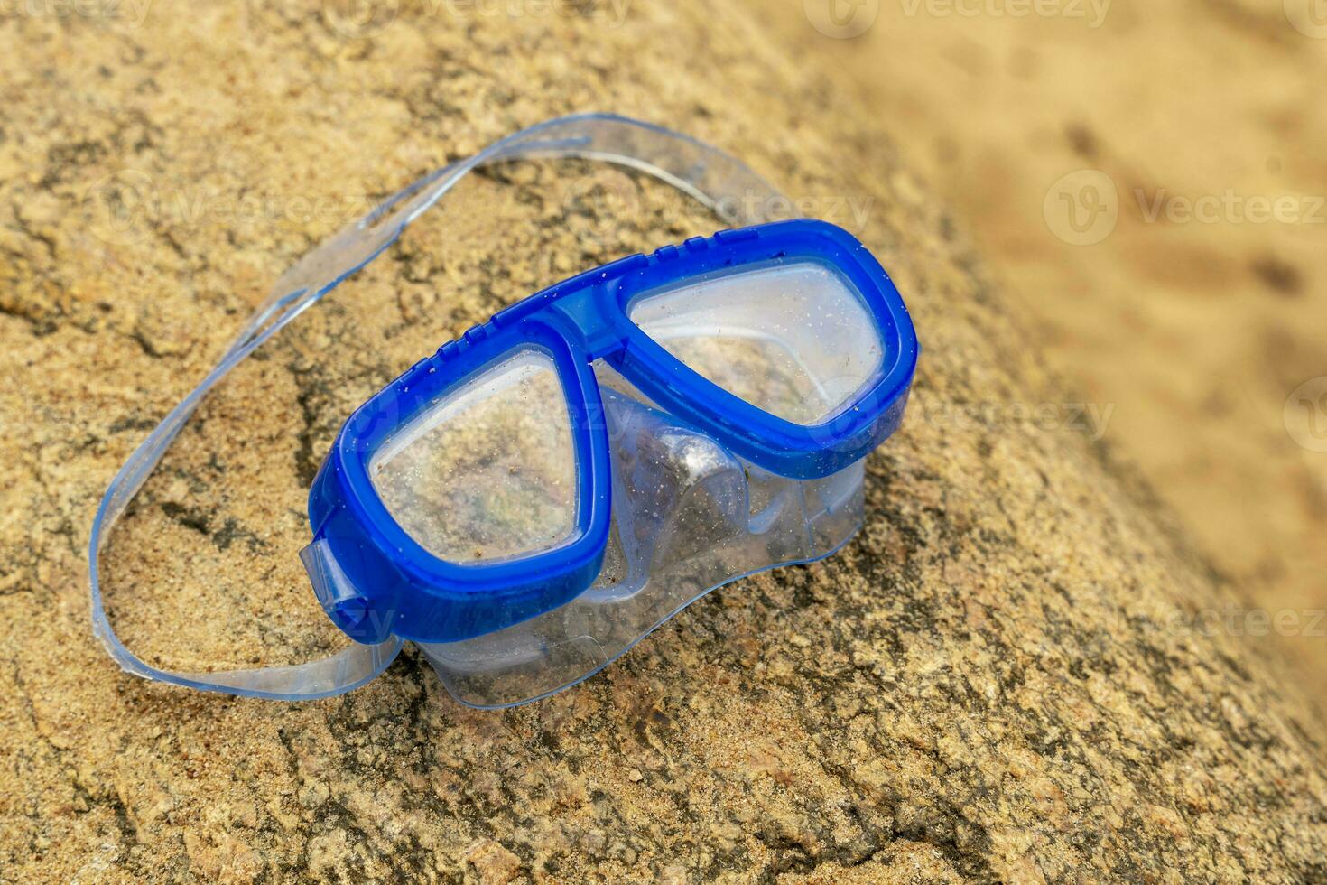 Children's swimming mask lying on a stone on the shore of the lake photo