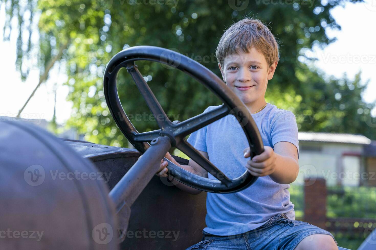 un chico conducción un antiguo Clásico tractor en el antecedentes de un ladrillo pared foto