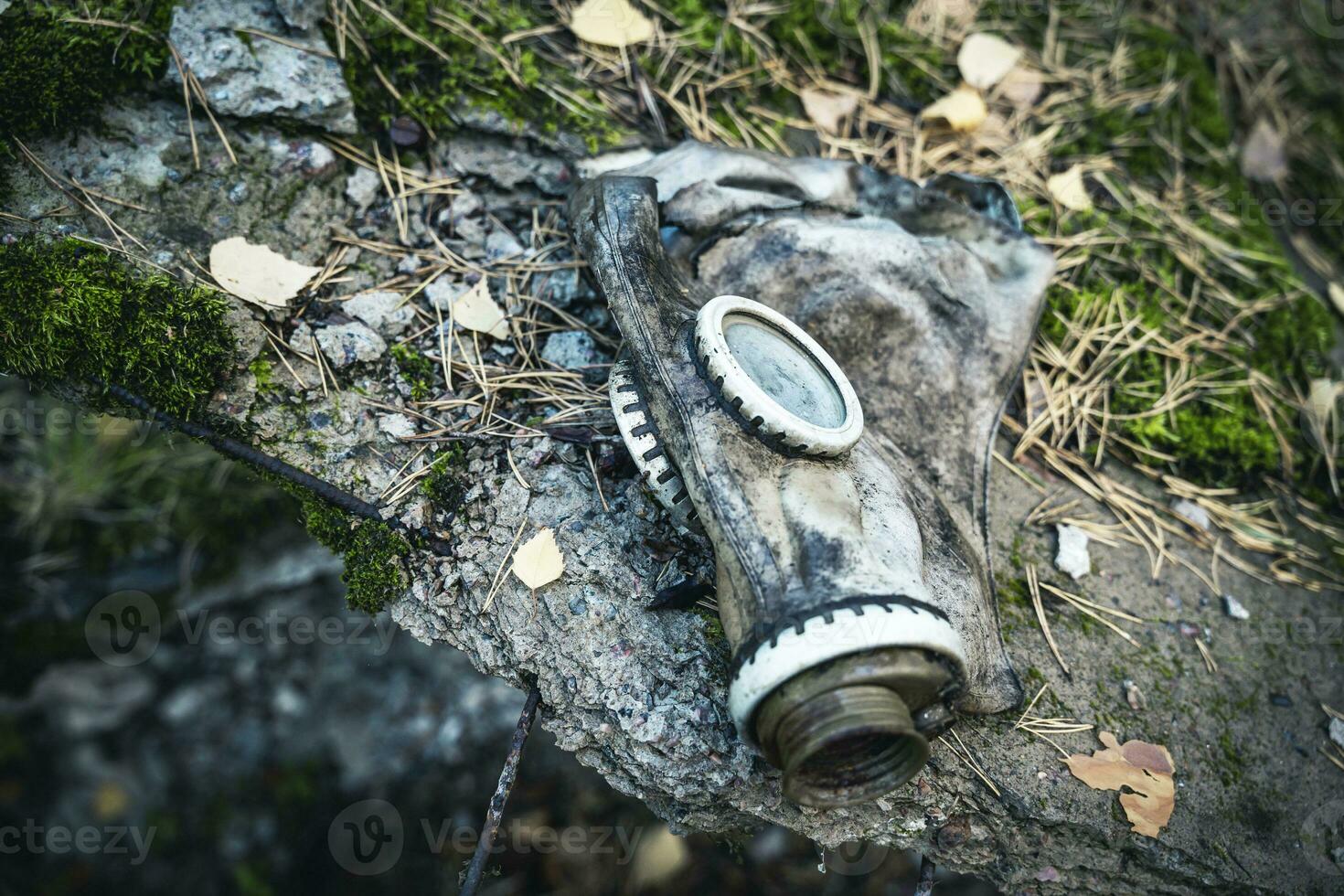 an old used gas mask lying on a large stone photo