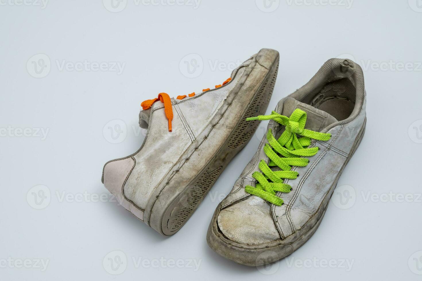 worn old torn white sneakers with colored laces on a white background photo