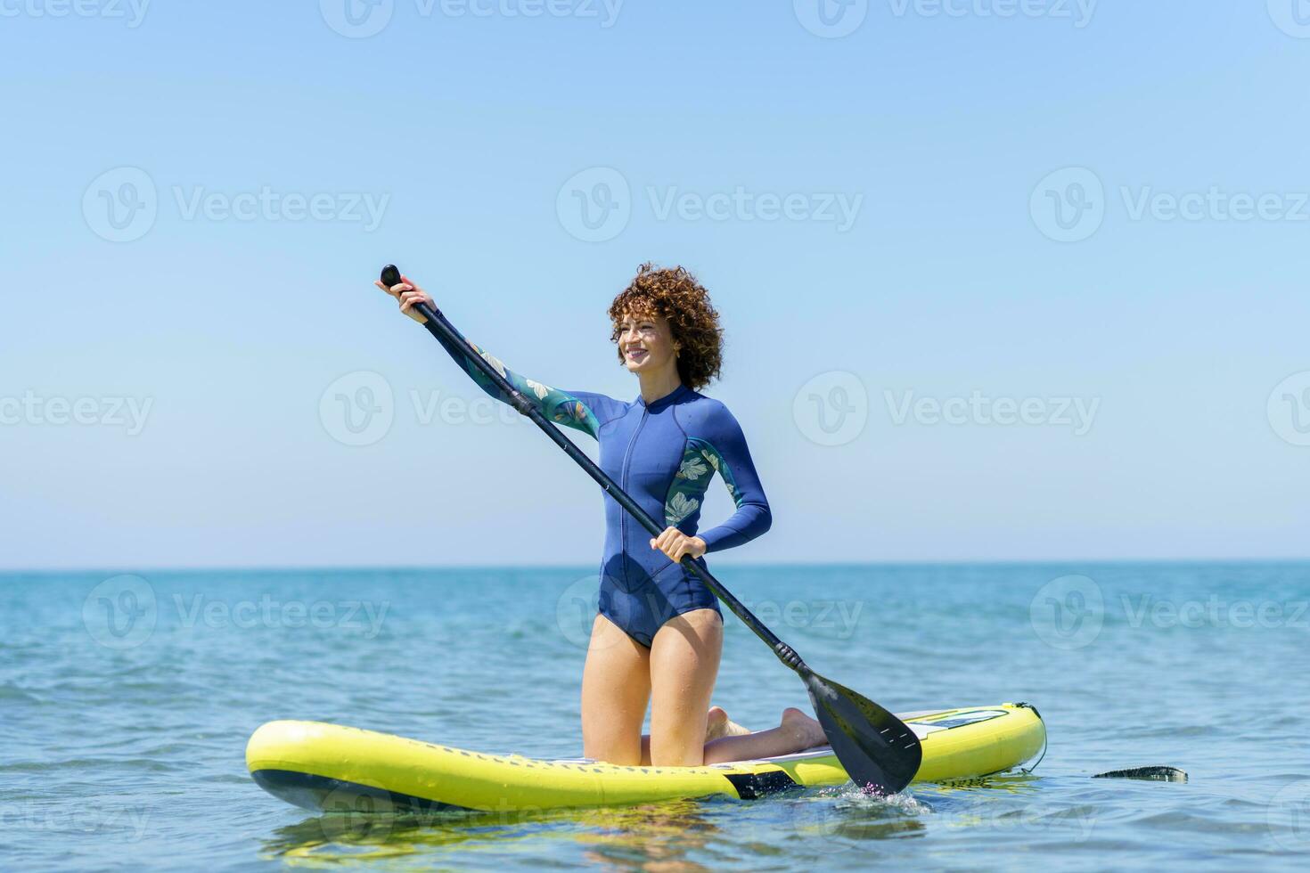Happy woman with paddle on board on sea photo