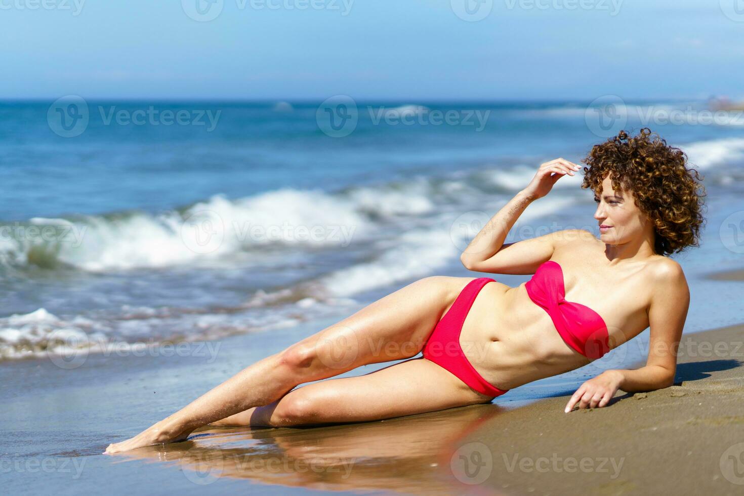 relajado Delgado mujer descansando en arenoso costa foto