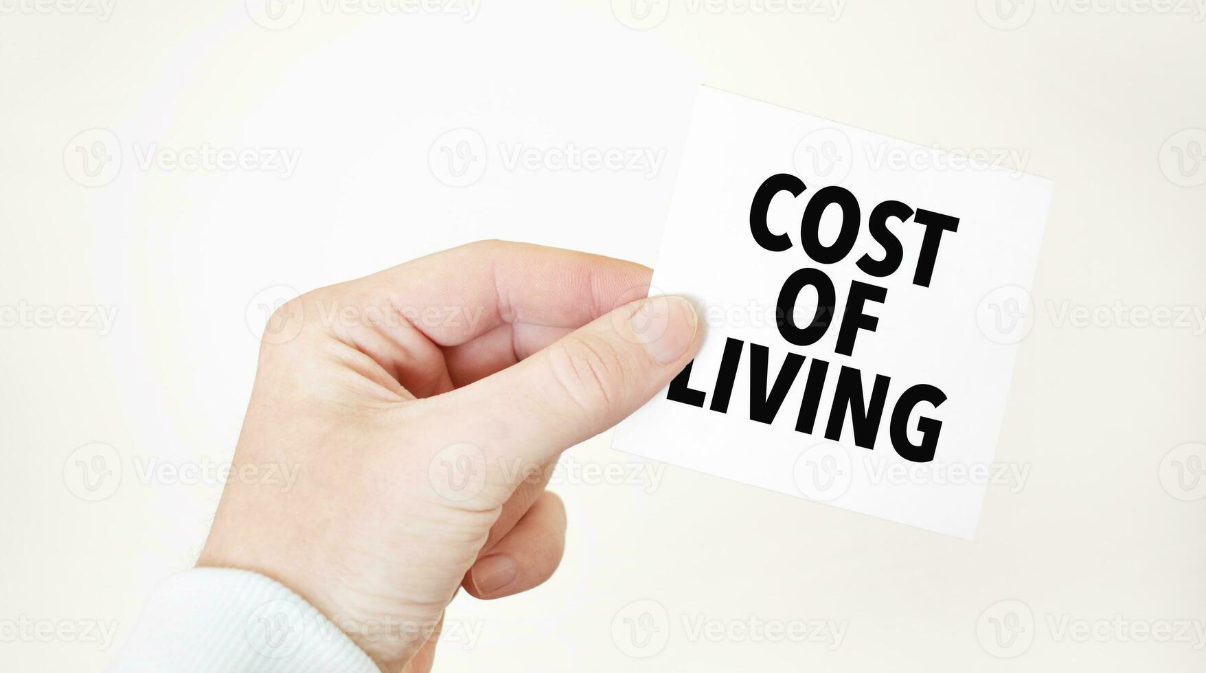 Businessman holding a card with text cost of living business concept photo