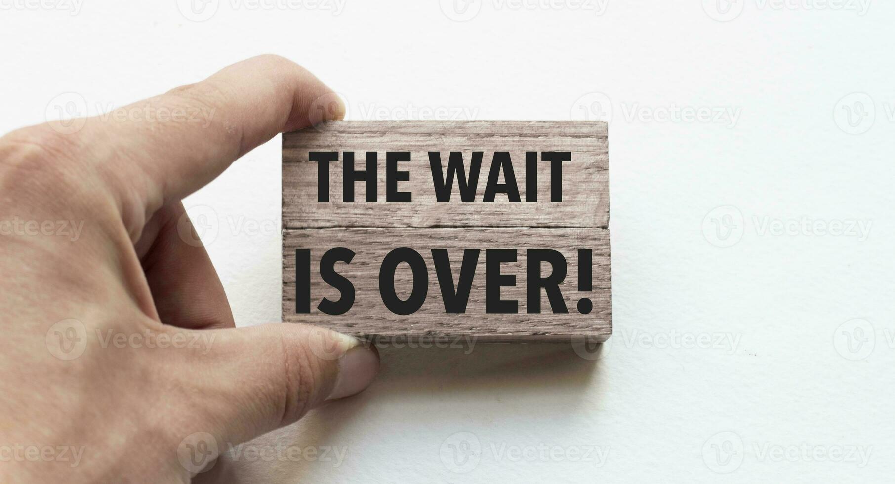 Hand of a businessman holding wooden blocks. Conceptual image. Text the wait is over concept business succeed. photo