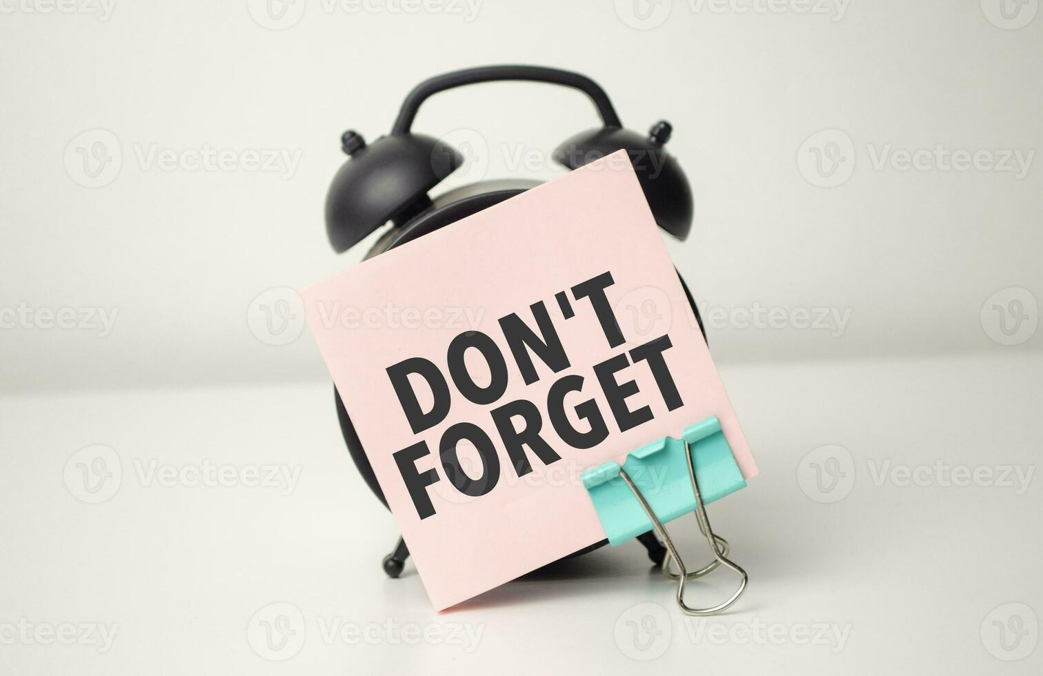 alarm clock with pink sticker with the text Don't forget photo