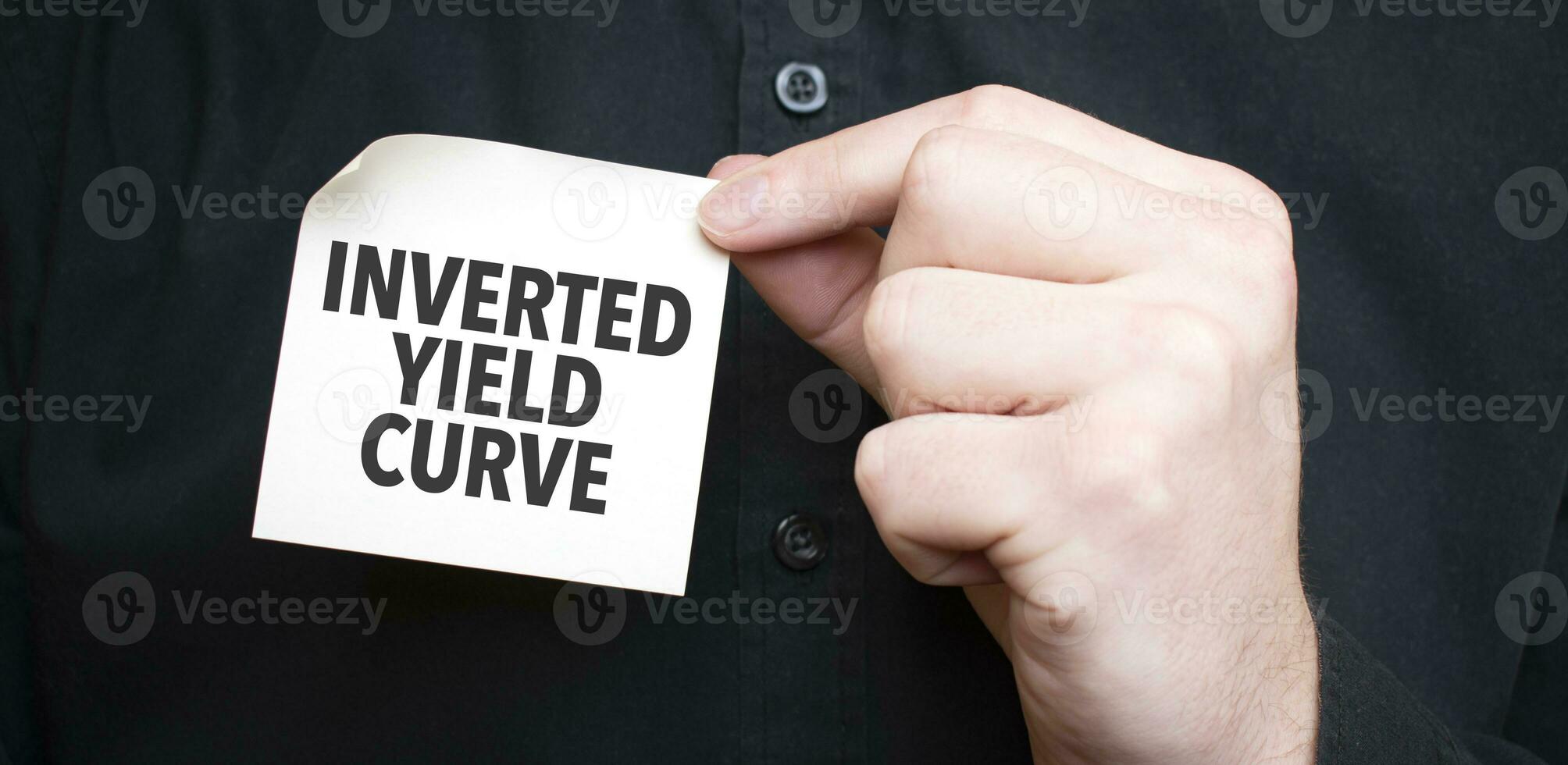 Businessman holding a card with text INVERTED YIELD CURVE, business concept photo