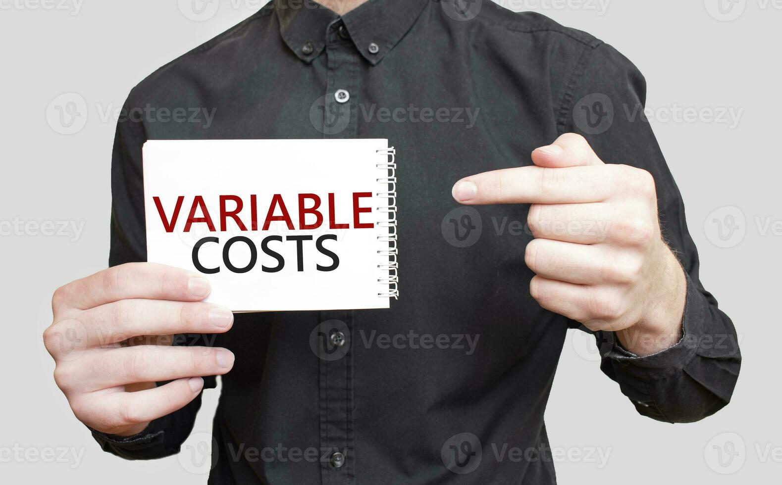 Businessman holding a white notepad with text variable costs, business concept photo