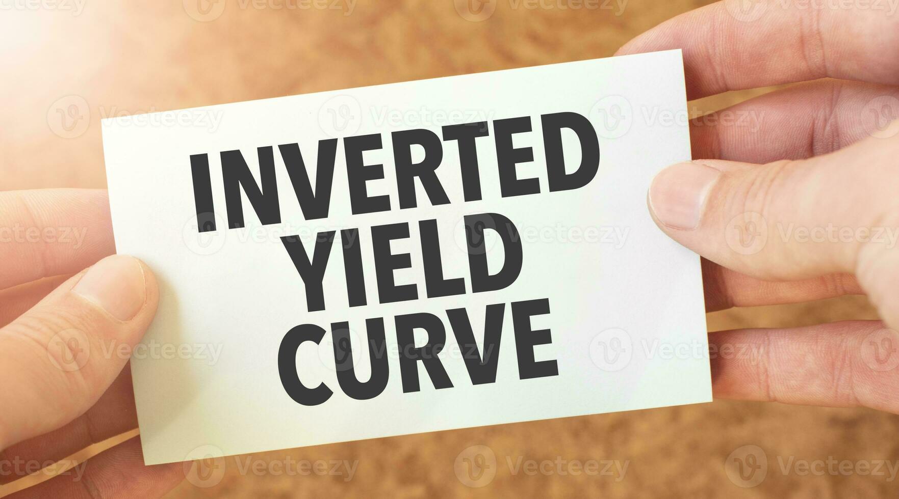 INVERTED YIELD CURVE word inscription on white card paper sheet in hands of a businessman. recap concept. red and white paper photo