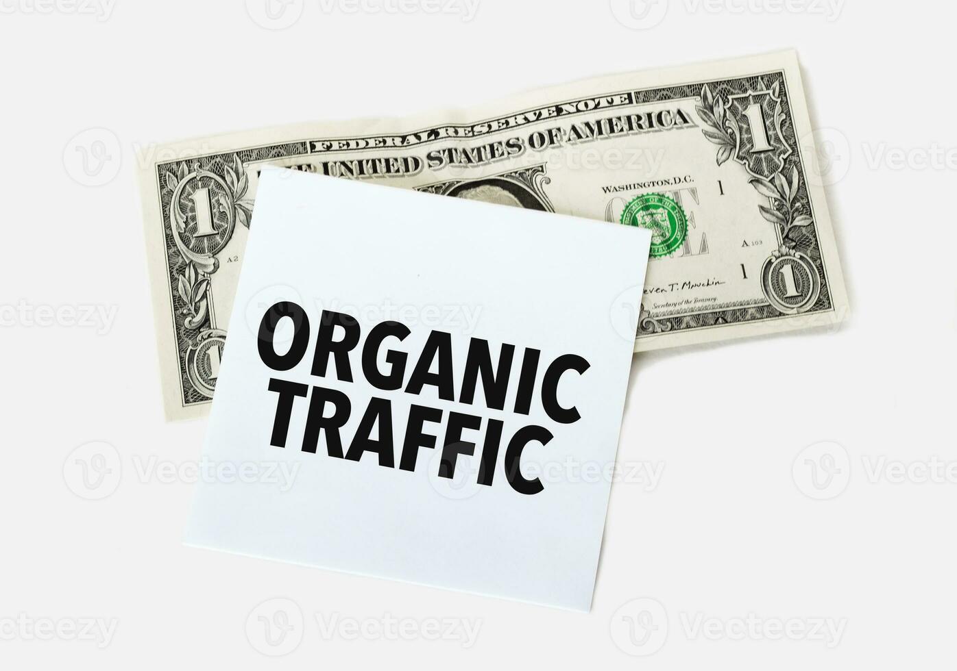 1 dollar bill and white notepad sheet on the white background. Text ORGANIC TRAFFIC photo