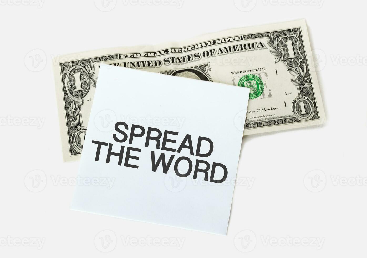 1 dollar bill and white notepad sheet on the white background. Text SPREAD THE WORD photo