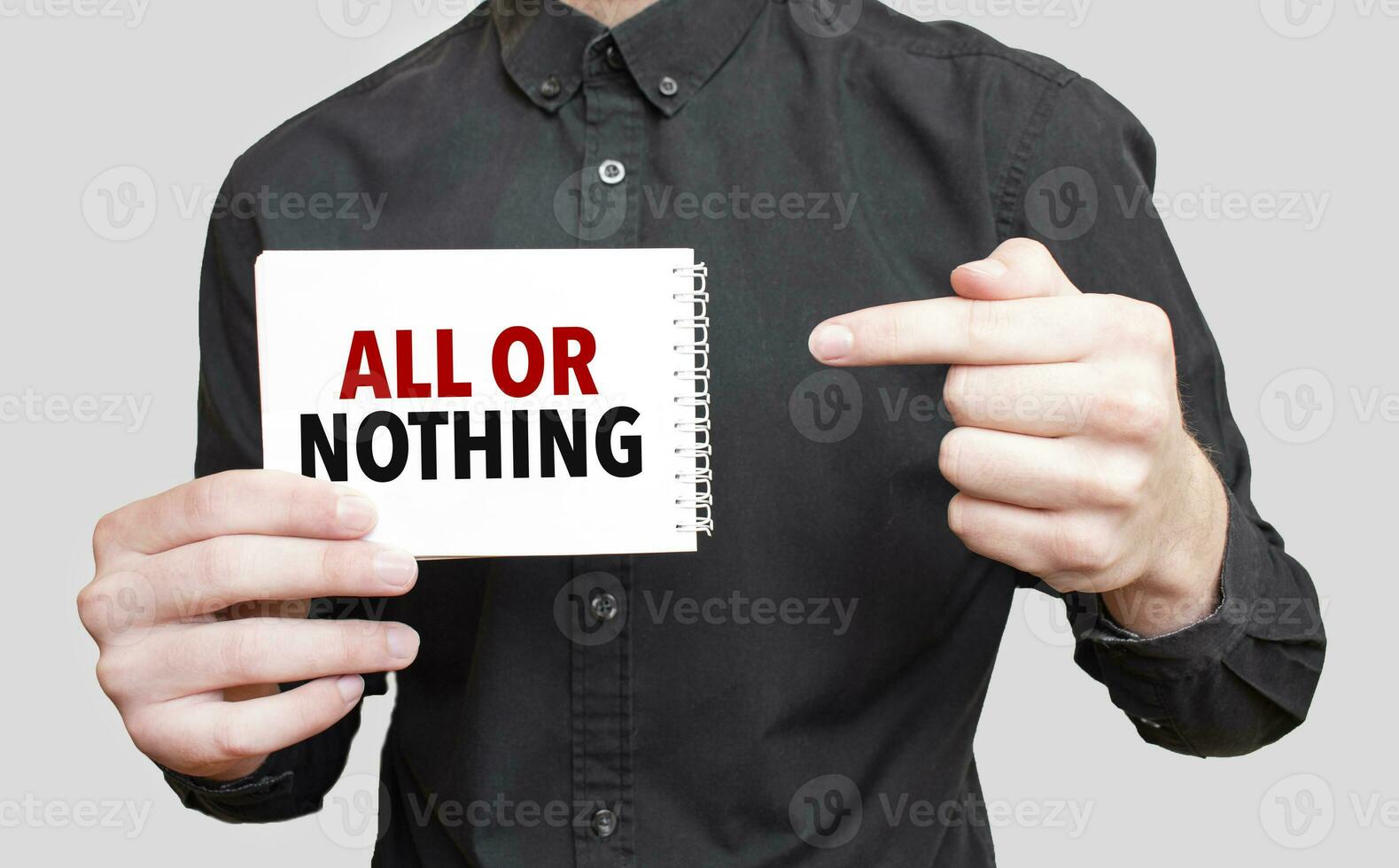 Businessman holding a white notepad with text ALL OR NOTHING, business concept photo