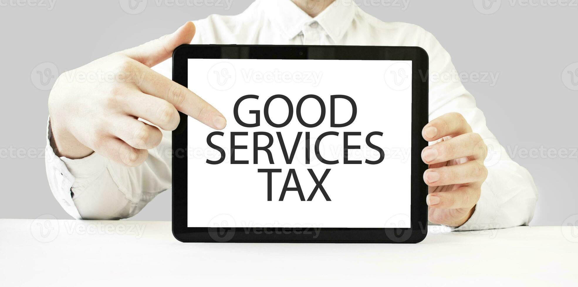 Text GOOD SERVICES TAX on tablet display in businessman hands on the white background. Business concept photo