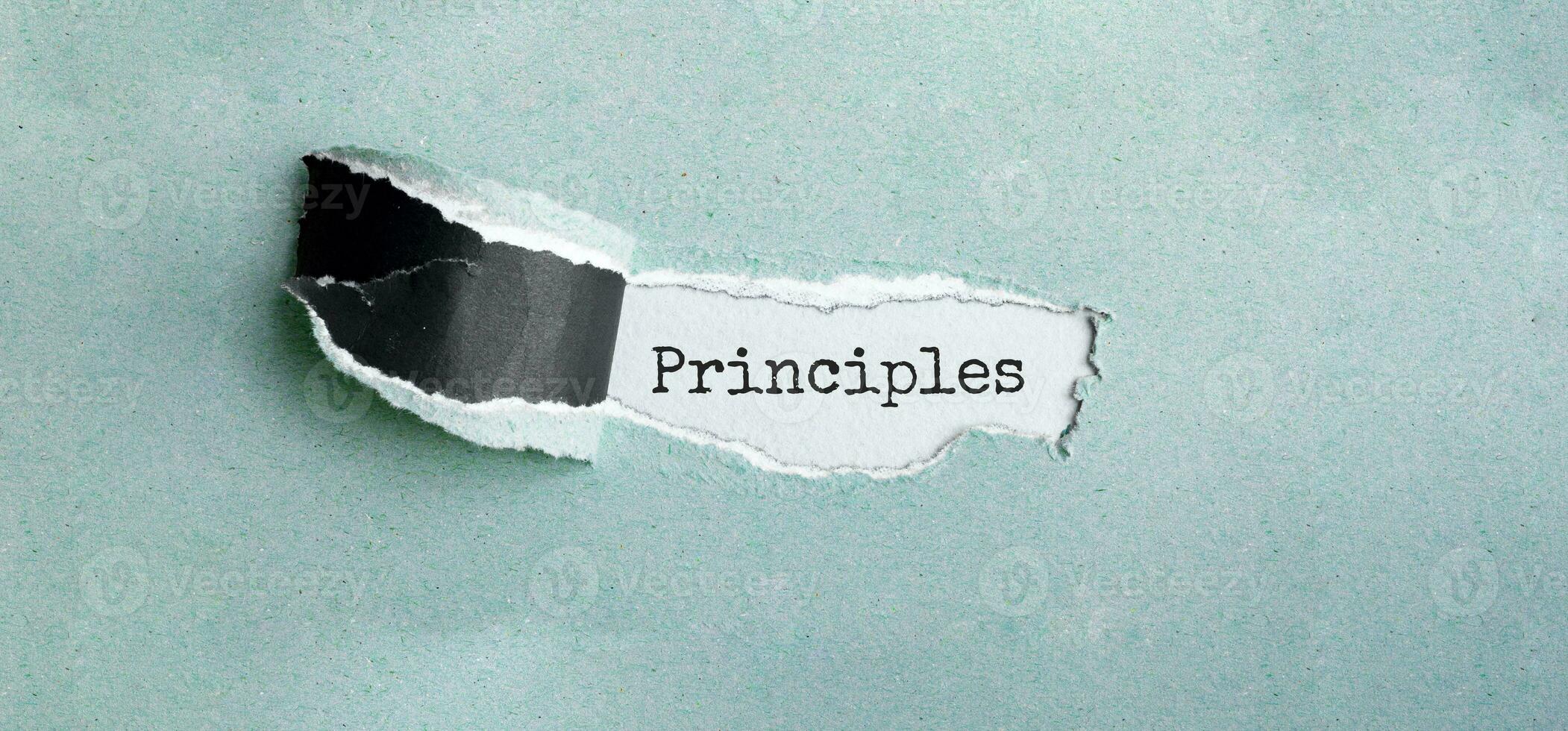 The text PRINCIPLES appearing behind torn green paper photo