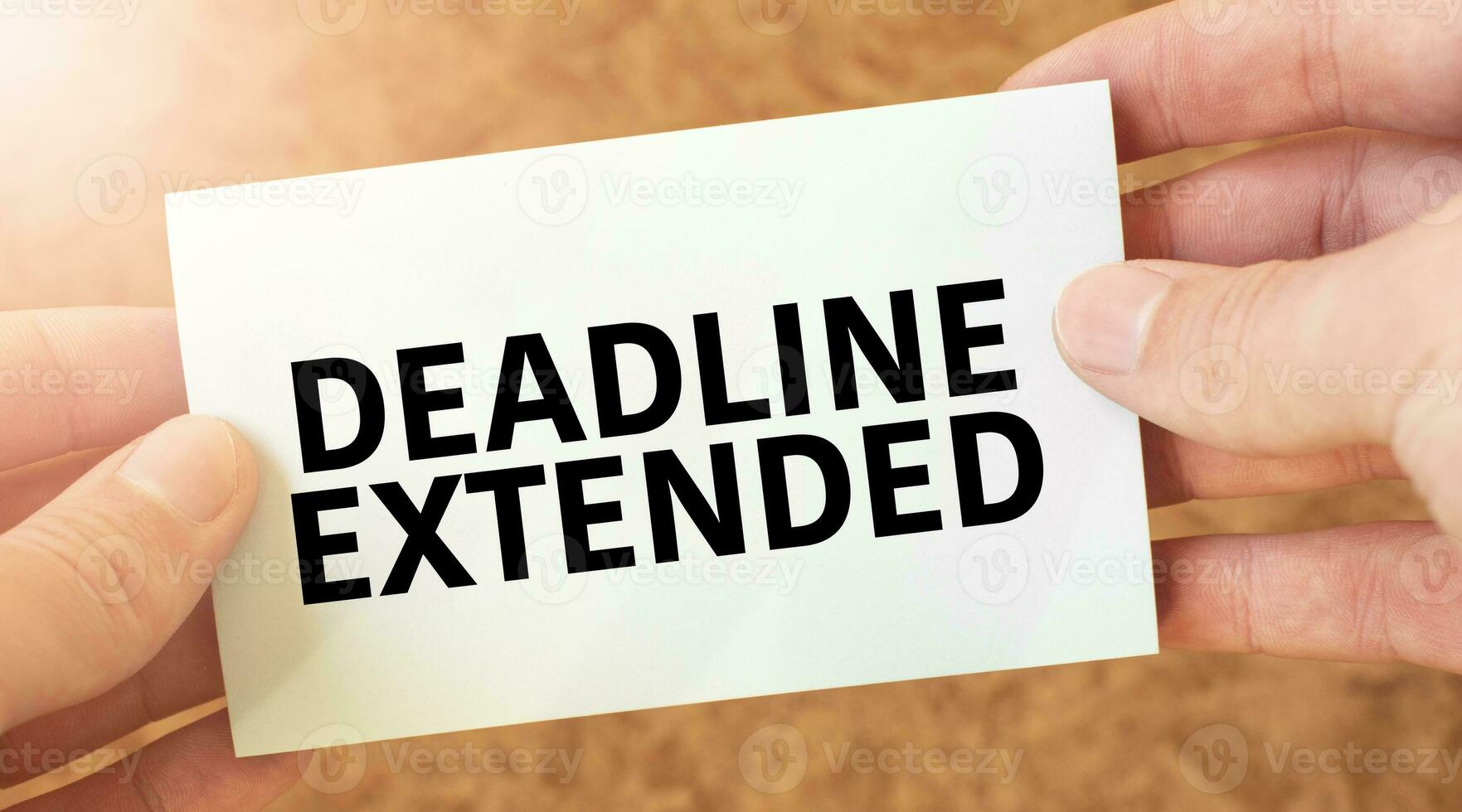 DEADLINE EXTENDED word inscription on white card paper sheet in hands of a businessman. recap concept. red and white paper photo