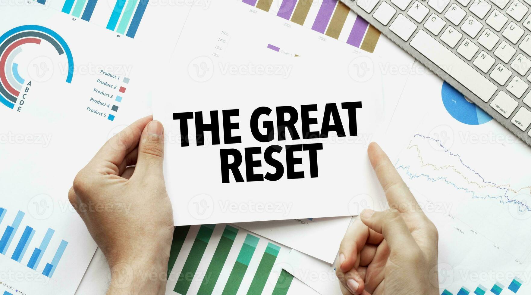 Businessman holding a card with text THE GREAT RESET .Keyboard, diagram and white background photo