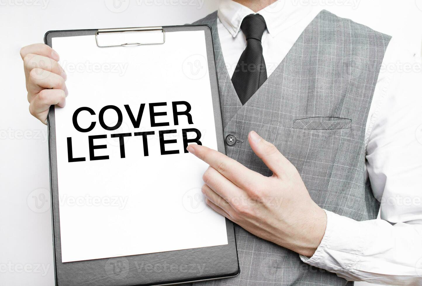 COVER LETTER inscription on a notebook in the hands of a businessman on a grey background, a man points with a finger to the text photo