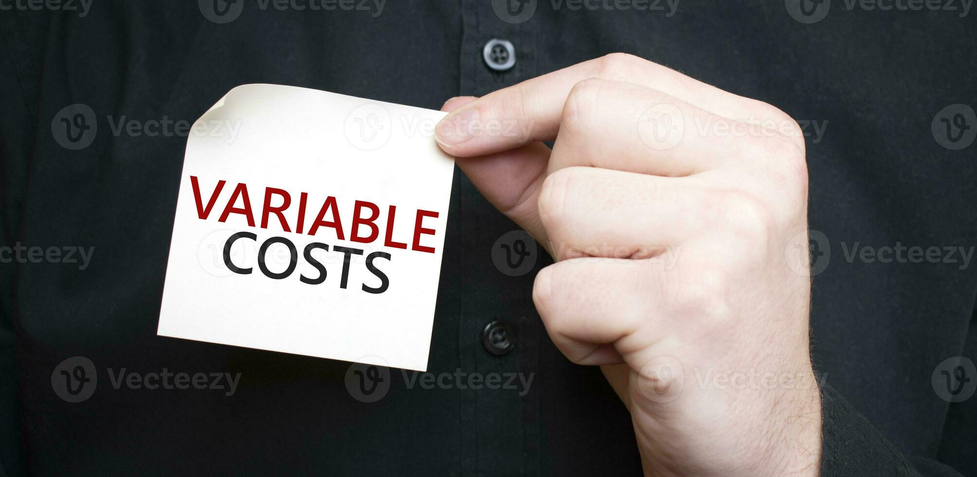 Businessman holding a card with text variable costs, business concept photo