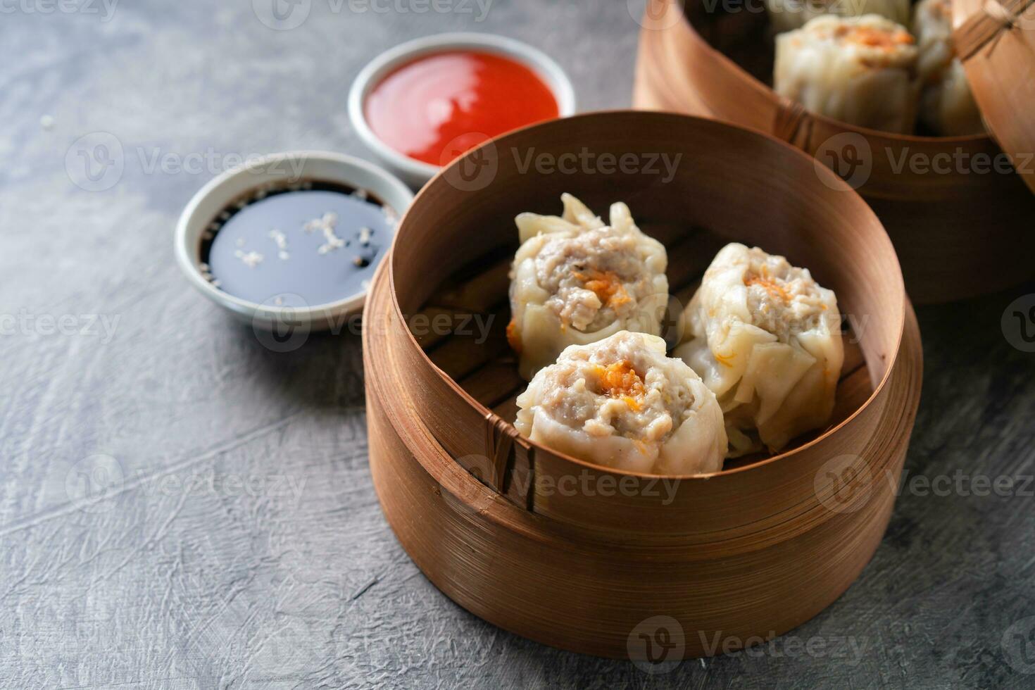 Chinese steamed dumplings or  Dim Sum with chopstick in bamboo steamer on dark abstract background photo