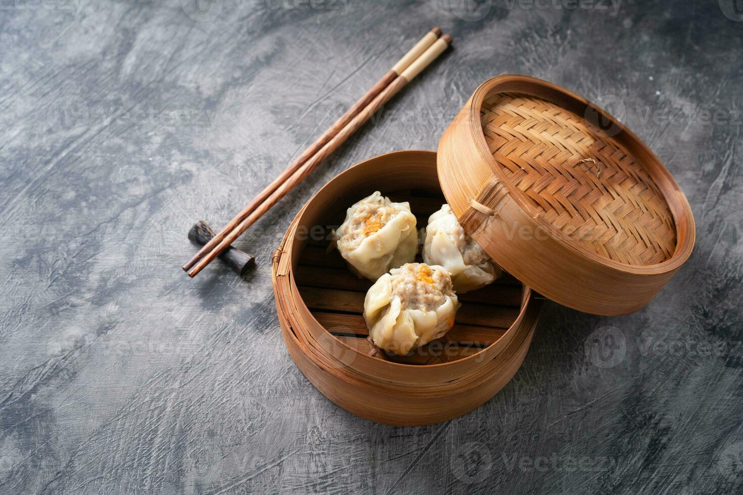 Chinese steamed dumplings or  Dim Sum in bamboo steamer on dark abstract background photo